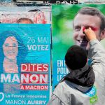 Un seguidor de Marion Aubry, candidata de La Francia Insumisa, pinta sobre un cartel de Macron/AP
