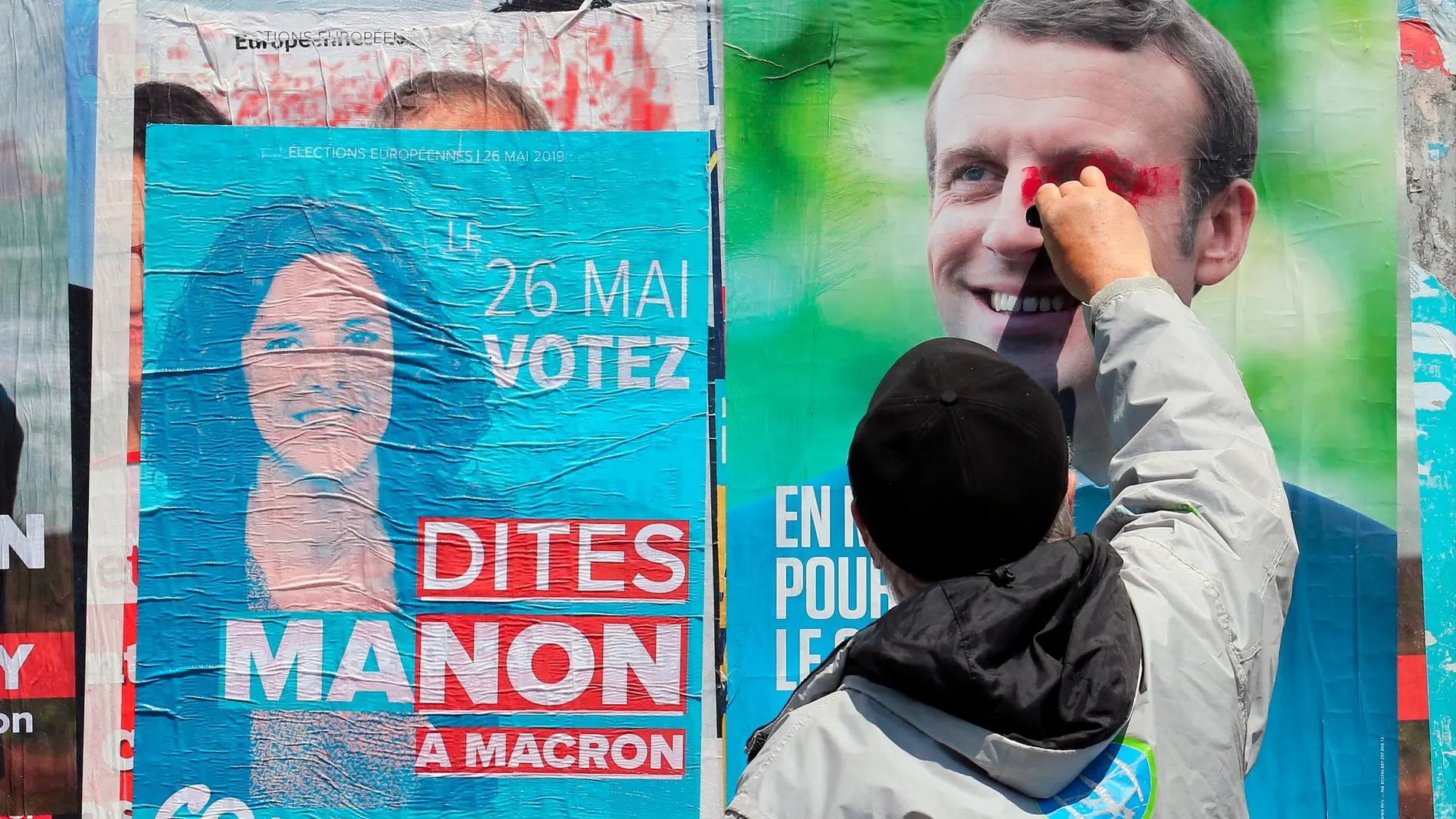 Un seguidor de Marion Aubry, candidata de La Francia Insumisa, pinta sobre un cartel de Macron/AP