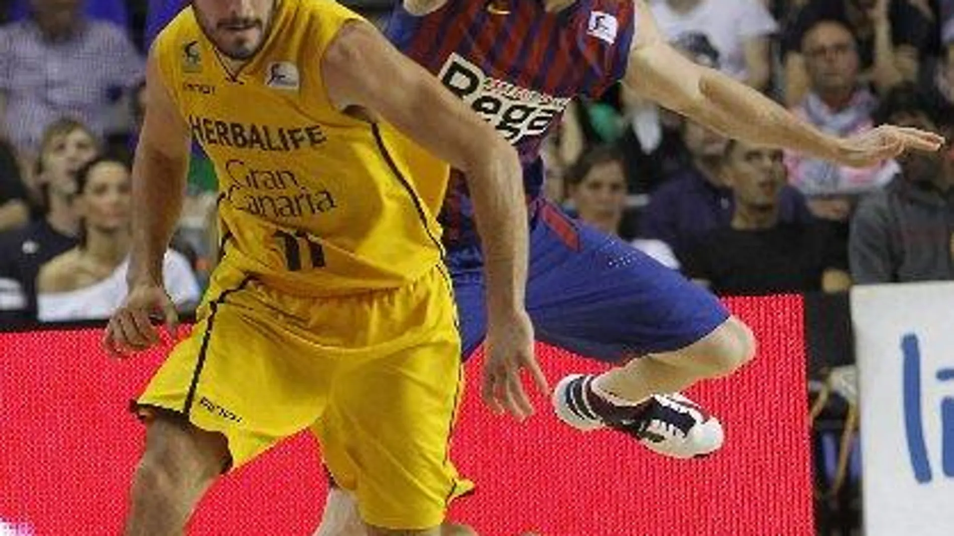 El base del Herbalife Gran Canaria Tomás Bellas (i) con el balón ante el base italiano del Regal Barcelona Marcelinho Huertas, durante el primer partido de la serie de semifinales al título de Liga ACB