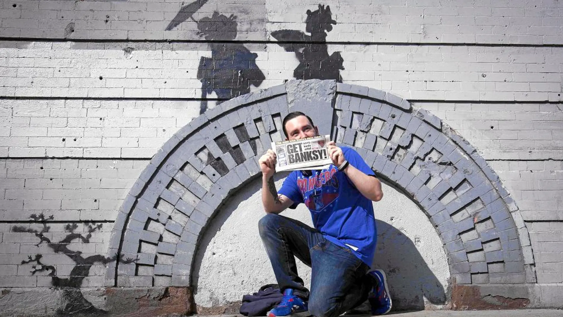 Un espontáneo posa delante de una de las obras que Bansky ha hecho en Nueva York