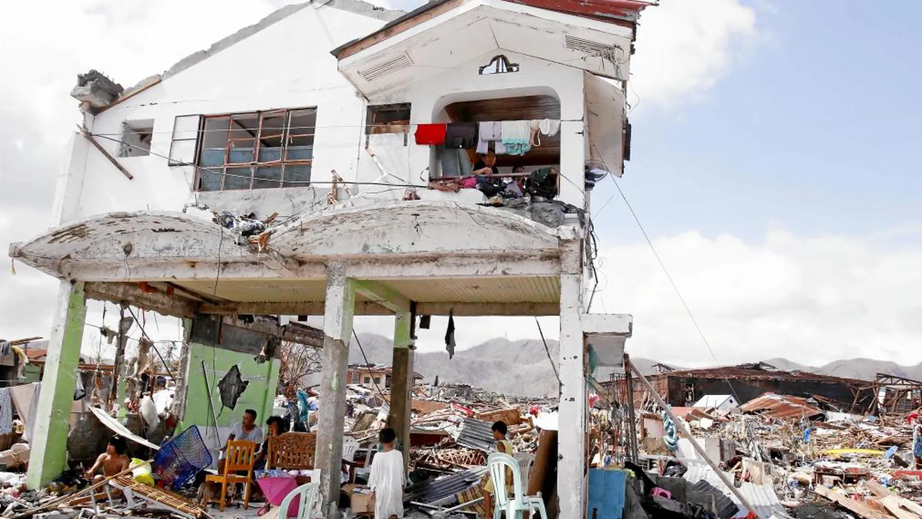 Una familia filipina observa el estado en el que ha quedado su casa tras el paso del tifón «Yolanda», en la ciudad de Tacloban