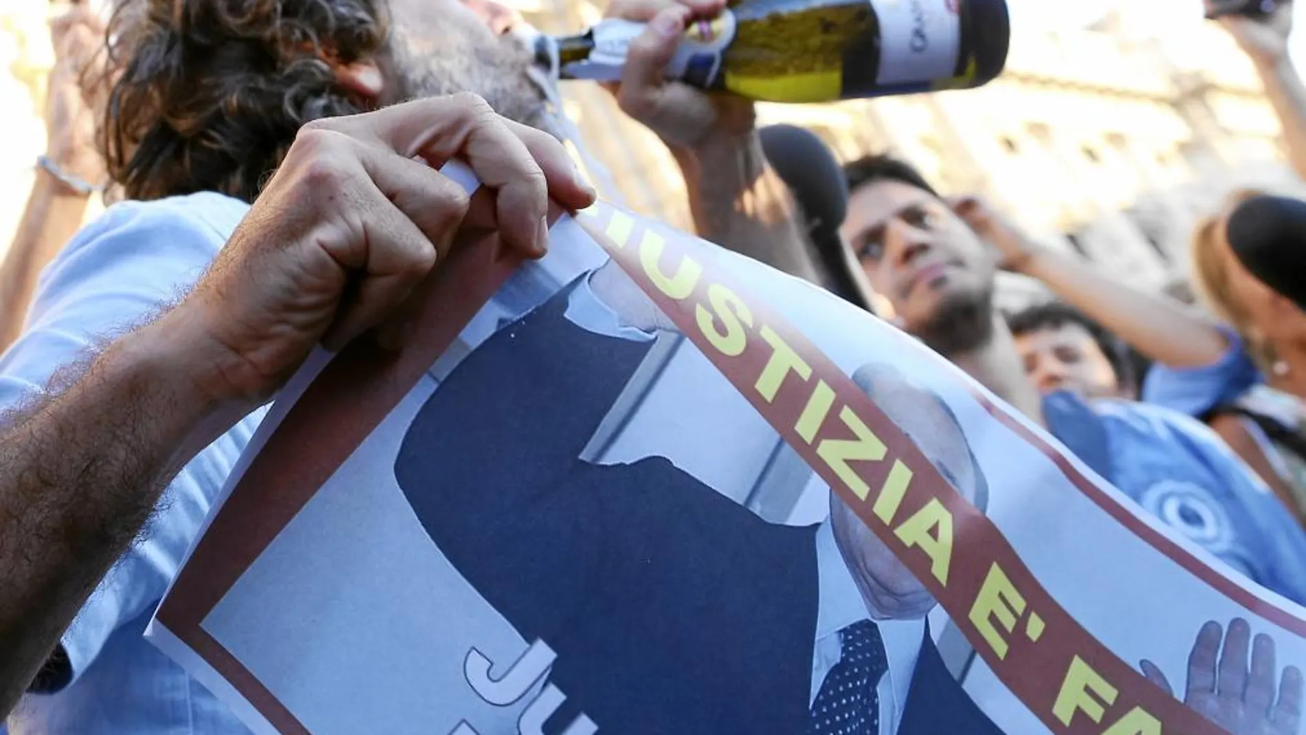 Un partidario de Berlusconi bebe para festejar la sentencia del ex primer ministro frente al tribunal de Roma