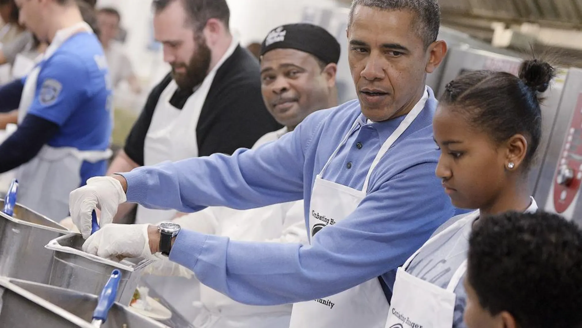 El presidente estadounidense, Barack Obama (3d), y su hija Sasha (2d) participan en un proyecto de servicios comunitarios en la D.C Central Kitchen como parte de la celebración del Día de Martin Luther King Jr. en Washington DC