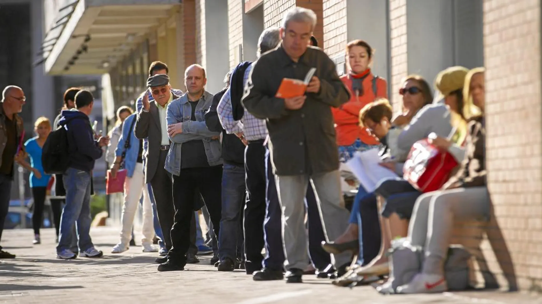 Varias personas hacen cola a las puertas de una oficina de empleo en Madrid