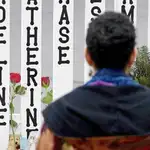 Una mujer observa una valla con los nombres de los niños asesinados