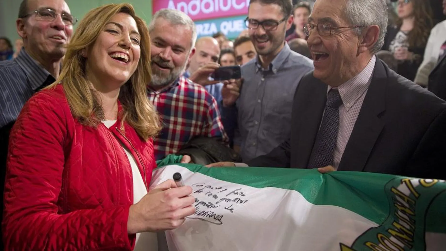 La presidenta de la Junta de Andalucía, Susana Díaz (i), firma una bandera de la comunidad a unos simpatizantes el pasado día 14