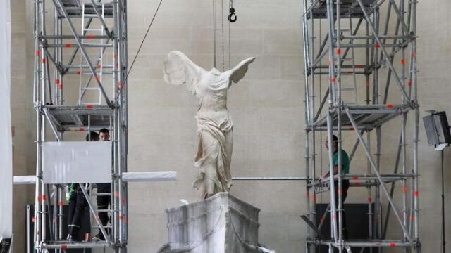 Momento de la instalación de la Victoria de Samotracia, la célebre estatua alada del siglo II a.C. que volvió hoy a su espacio monumental tras diez meses de restauración.