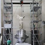 Momento de la instalación de la Victoria de Samotracia, la célebre estatua alada del siglo II a.C. que volvió hoy a su espacio monumental tras diez meses de restauración.