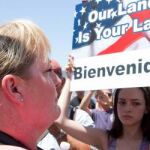 Una mujer sostiene un letrero que dice: "Nuestra tierra es tu tierra. Bienvenidos"durante una manifestación hoy, viernes 4 de julio 2014, frente al Centro de Procesamiento de La Patrulla Fronteriza en Murrieta, California (EE.UU.).