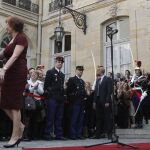 El primer ministro saliente, Jean-Marc Ayrault, y su esposa, abandonan el Hotel Matignon, mientras el nuevo primer ministro, Manuel Valls les mira desde la entrada.