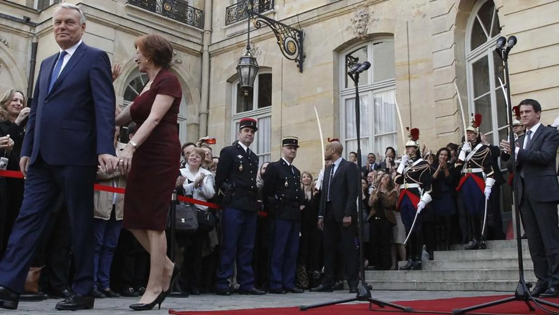 El primer ministro saliente, Jean-Marc Ayrault, y su esposa, abandonan el Hotel Matignon, mientras el nuevo primer ministro, Manuel Valls les mira desde la entrada.