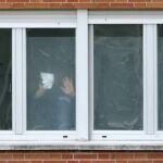 Un operario coloca plásticos traslúcidos en las ventanas de los ingresados en el Carlos III