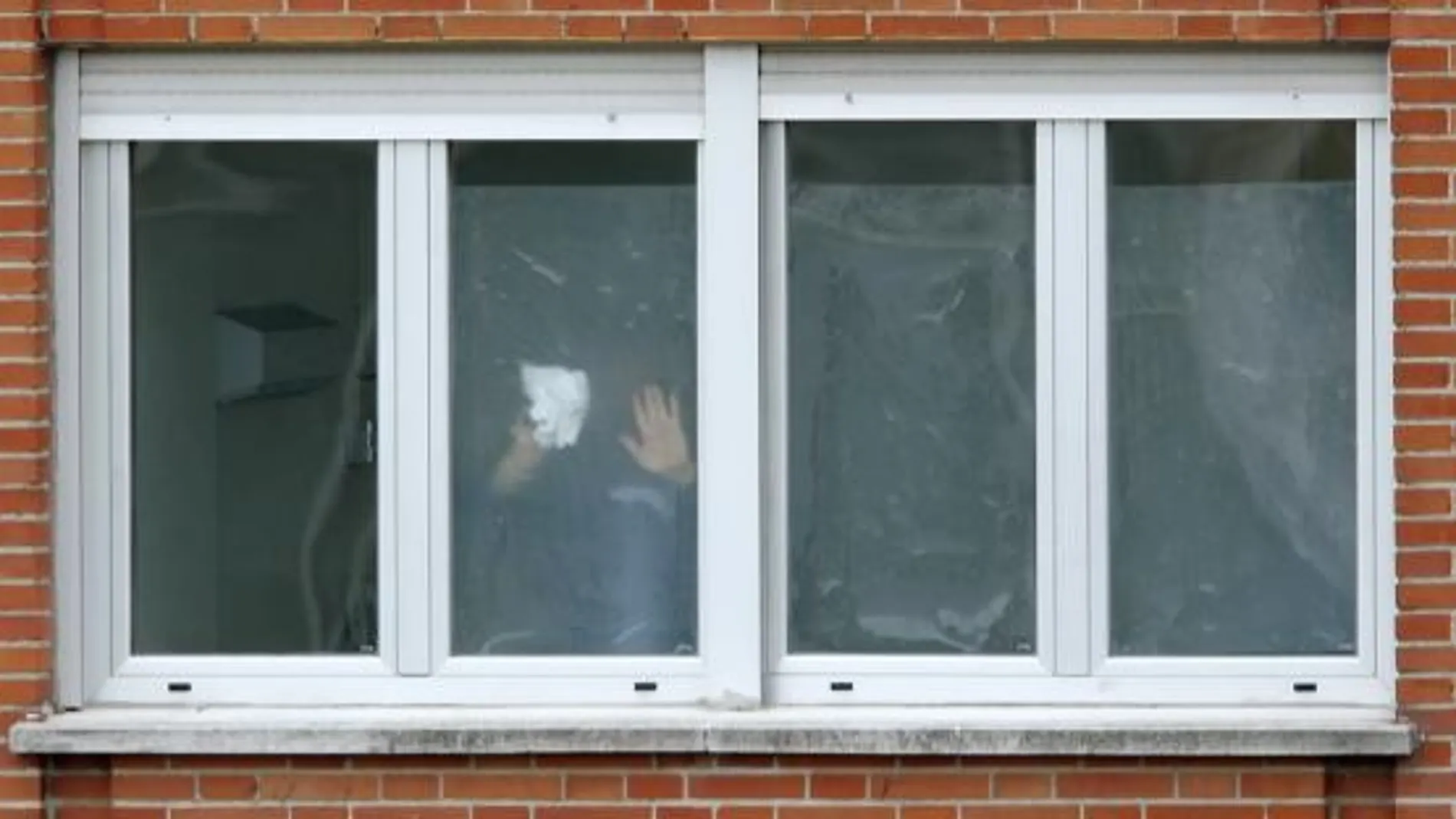 Un operario coloca plásticos traslúcidos en las ventanas de los ingresados en el Carlos III