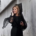 Una mujer vestida con el tradicional traje de mantilla habla por teléfono mientras se dirige a la salida de la Cofradía de Jesús Caído de Córdoba