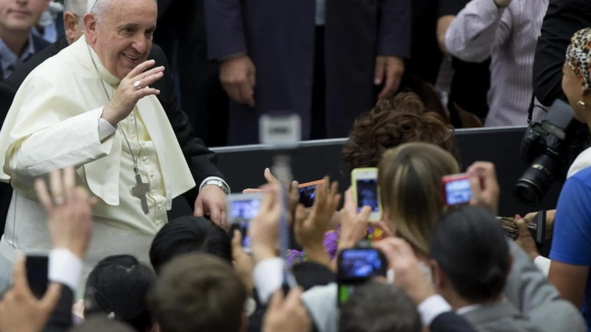 El Papa Francisco saluda a sus seguidores que le fotografían antes de comenzar la audiencia pública de los miércoles en el Aula Nervi (Vaticano)