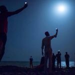 «SEÑAL». La imagen muestra a personas sin rostro que se amparan en la noche de Yibuti mientras buscan red de teléfono para hablar con sus seres queridos