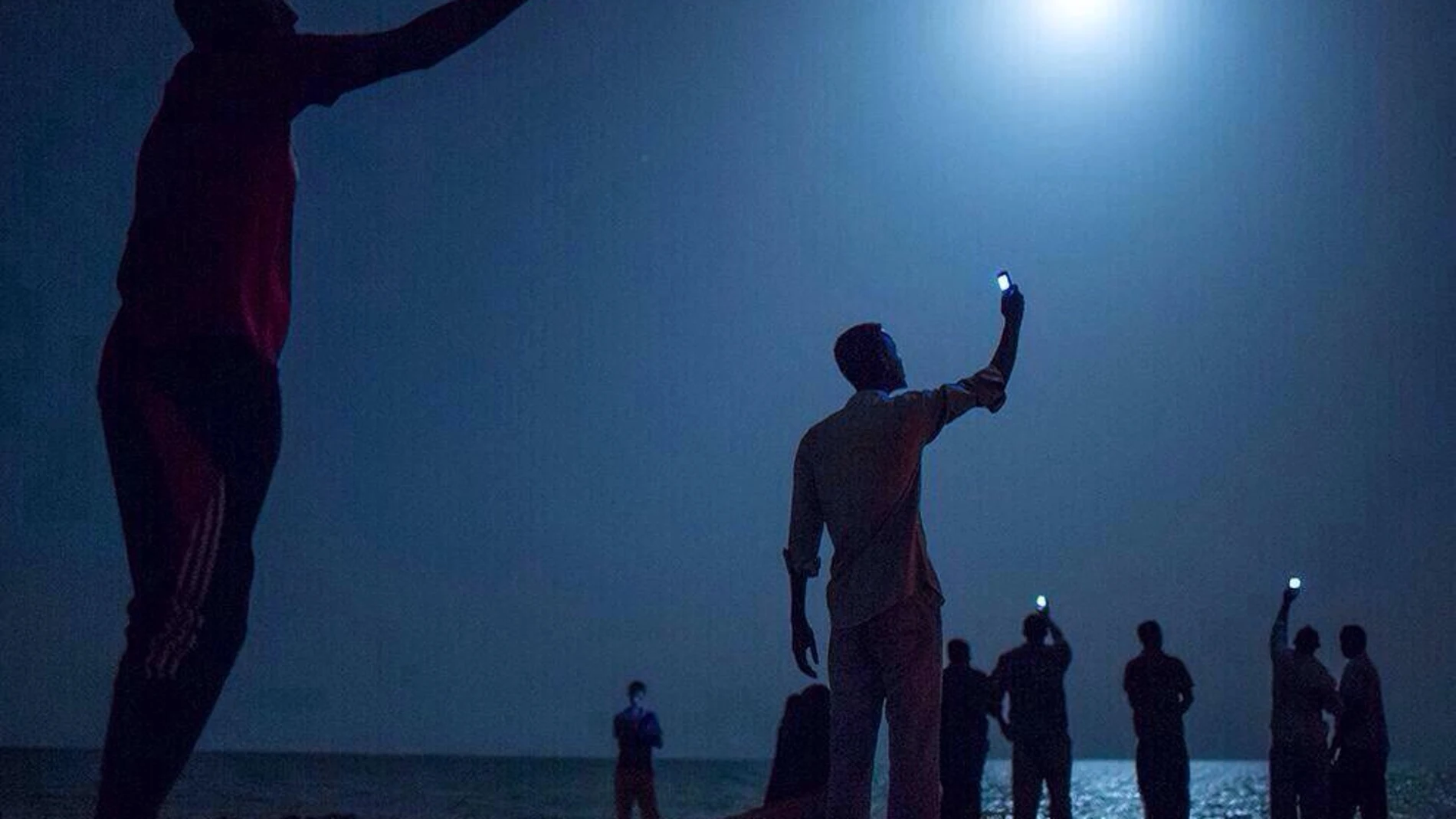 «SEÑAL». La imagen muestra a personas sin rostro que se amparan en la noche de Yibuti mientras buscan red de teléfono para hablar con sus seres queridos