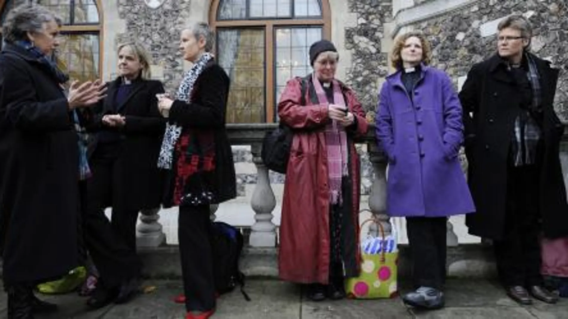 Varias pastoras anglicanas esperan en la puerta de la sede de la Iglesia anglicana, en Londres.