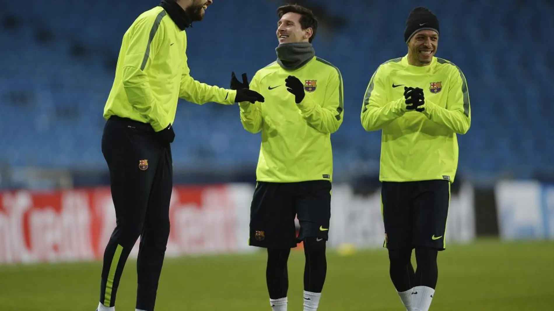 Piqué (i), bromea con sus compañeros, Lionel Messi (c) y Adriano Correia (d) durante el entrenamiento del equipo celebrado en el estadio Etihad de Manchester