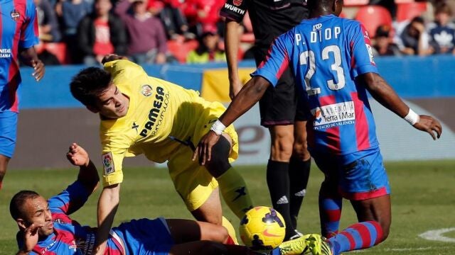 El centrocampista del Villarreal, Manuel Trigueros (c), ante el marroquí Nabil El Zhar (i) y el senegalés Pape Diop (d), del Levante