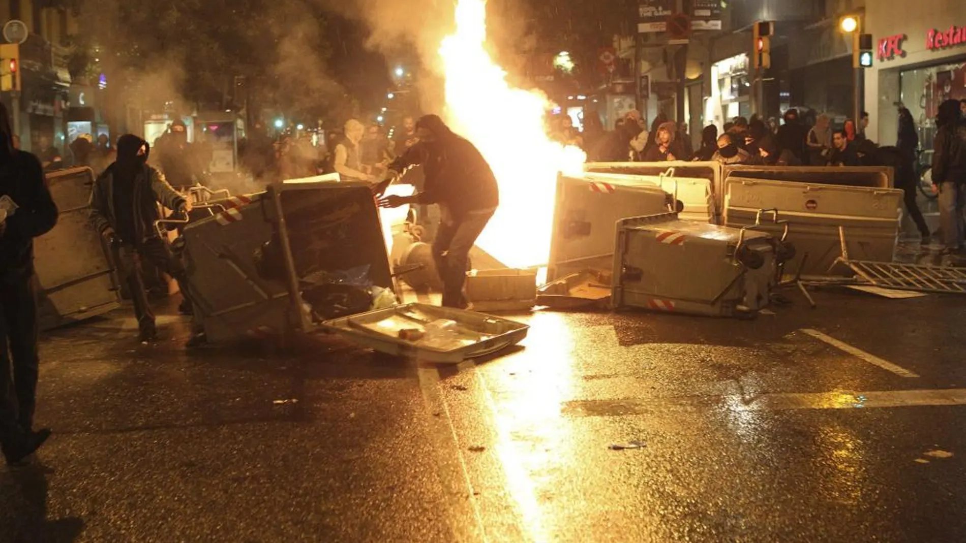Varios jóvenes vuelcan y queman contenedores formando barricadas durante los incidentes producidos tras una manifestación llevada a cabo en el barrio de Sants de Barcelona.