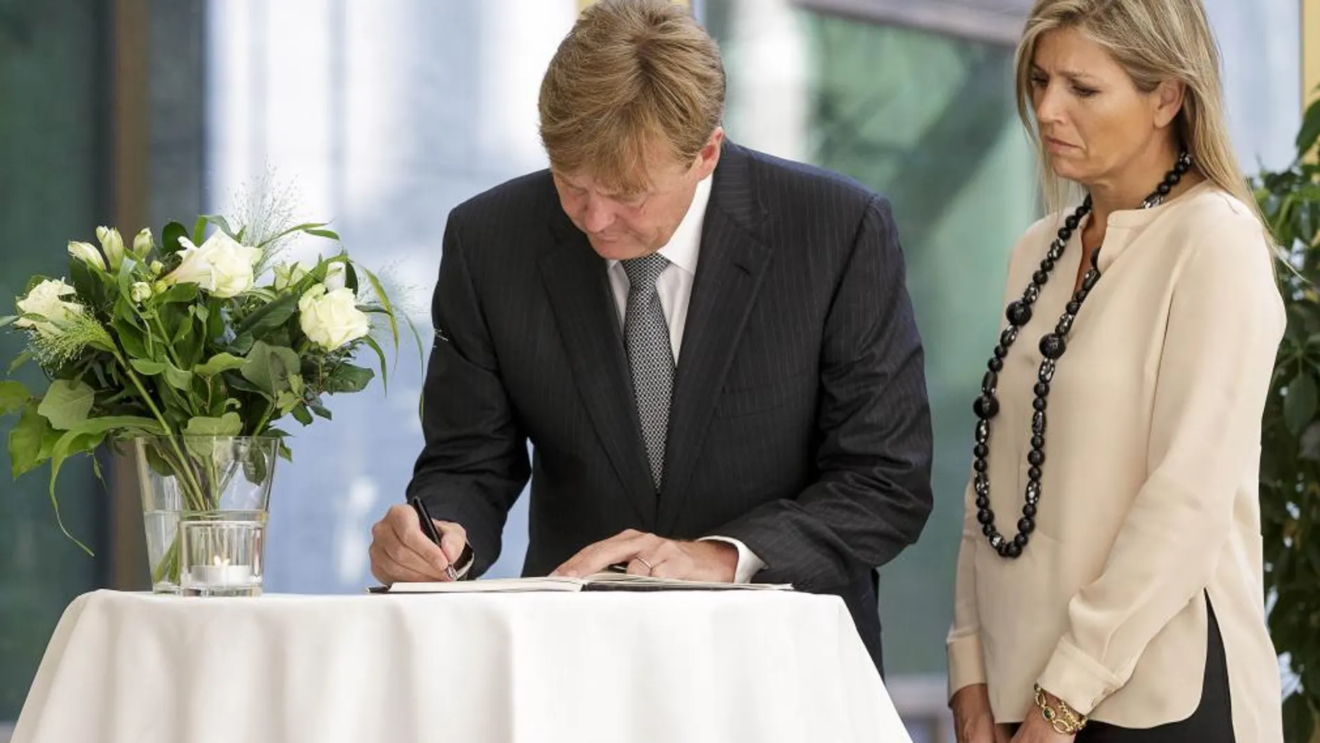 El Rey Guillermo Alejandro de Holanda firma en el libro de condolencias junto a la Reina Máxima en La Haya.