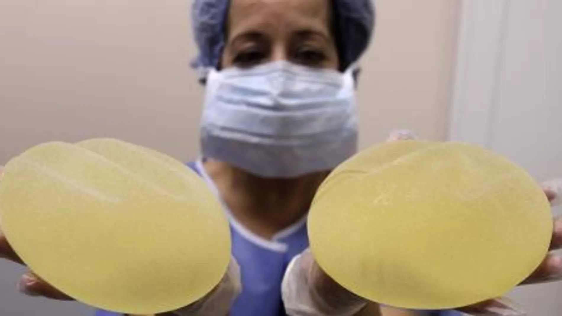 Una enfermera muestra dos implantes mamarios PIP.