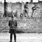 Un policía de Berlín delante de obrero que aumentan la altura del muro, en una imagen del 7 de octubre de 1961