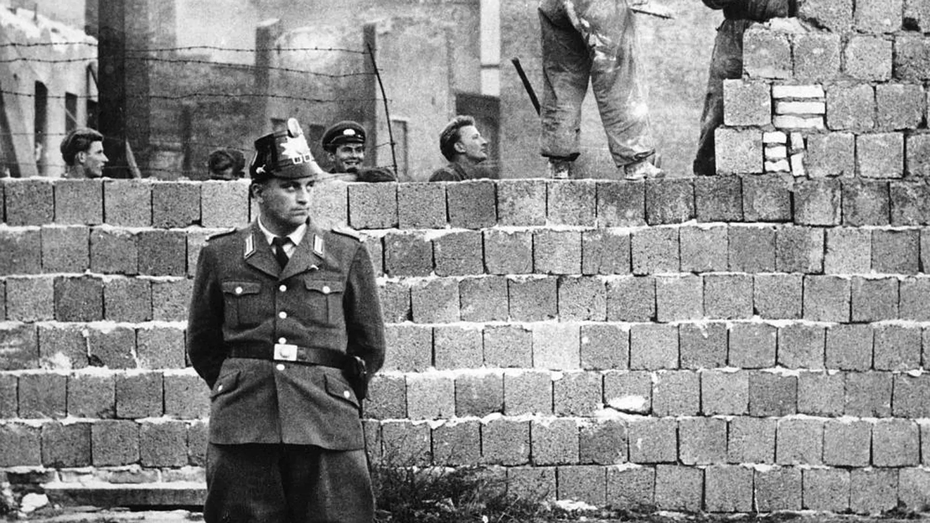 Un policía de Berlín delante de obrero que aumentan la altura del muro, en una imagen del 7 de octubre de 1961