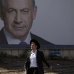 Un judio ortodoxo pasa ante un cartel de Benjamin Netanyahu