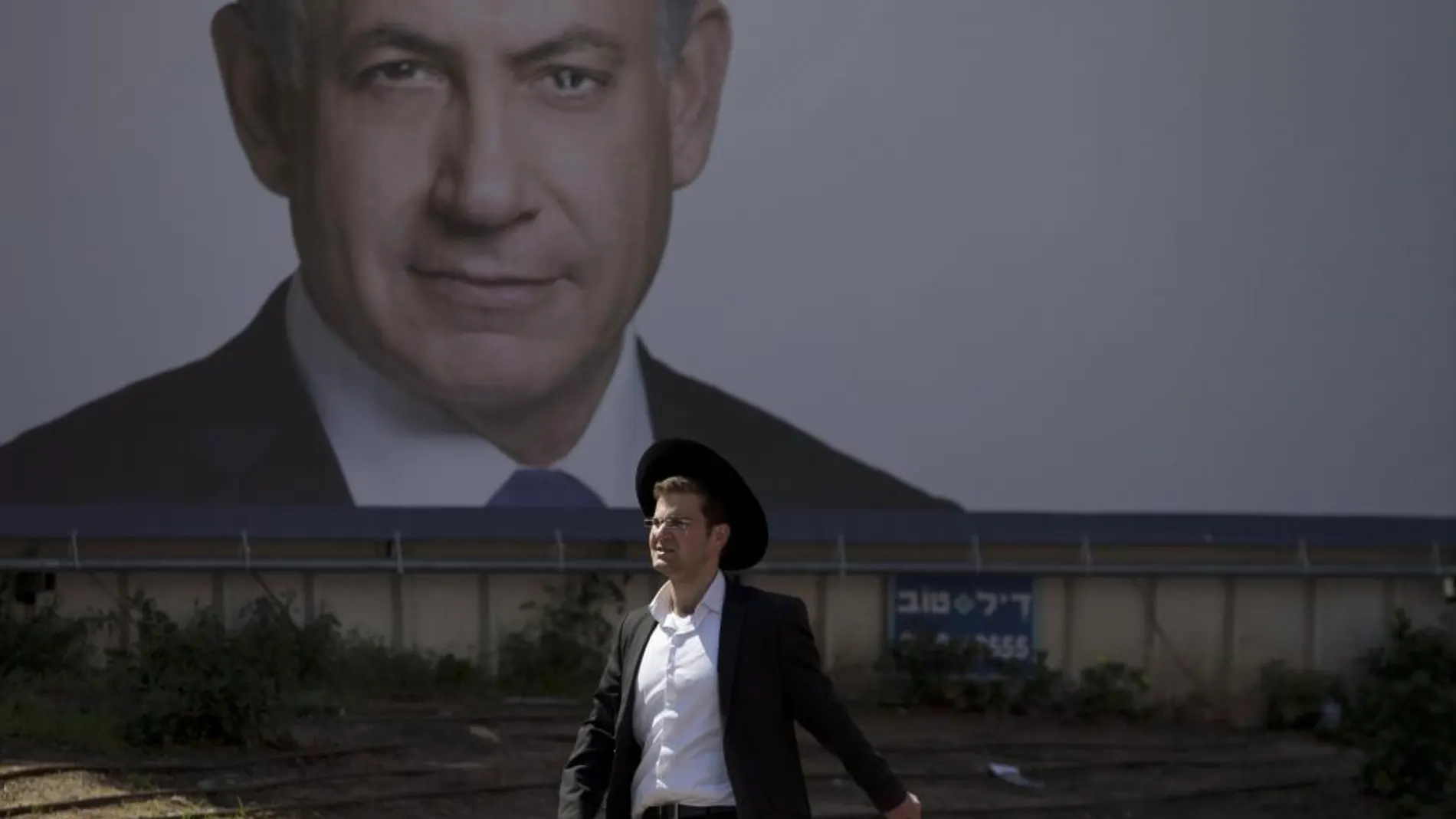 Un judio ortodoxo pasa ante un cartel de Benjamin Netanyahu