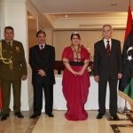 El embajador libio Mohamed Alfaqeeh Saleh y su señora Ben Ahmed, acompañados de miembros de la embajada, flanqueados por las banderas de España y Libia.