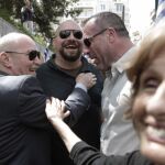 Los miembros del partido neonazi griego Amanecer Dorado (JA) Michalis Arvanitis (i), Panagiotaros (c) y Nikos Michos (2d) sonríen al ser recibidos por un seguidor del partido a las afueras de la corte de apelaciones en Atenas