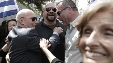 Los miembros del partido neonazi griego Amanecer Dorado (JA) Michalis Arvanitis (i), Panagiotaros (c) y Nikos Michos (2d) sonríen al ser recibidos por un seguidor del partido a las afueras de la corte de apelaciones en Atenas