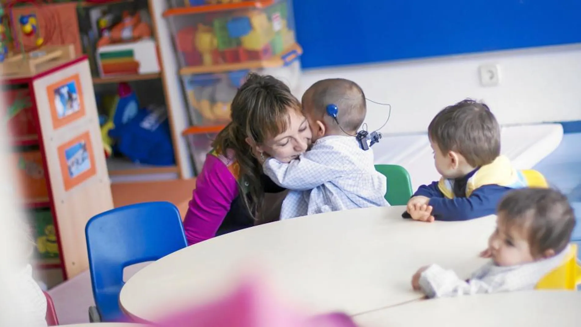 Uno de los alumnos de Educación Infantil del colegio Tres Olivos con discapacidad auditiva abraza a su profesora