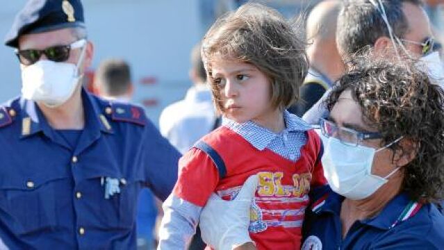 Una voluntaria recoge a un niño que llegó ayer a Sicilia