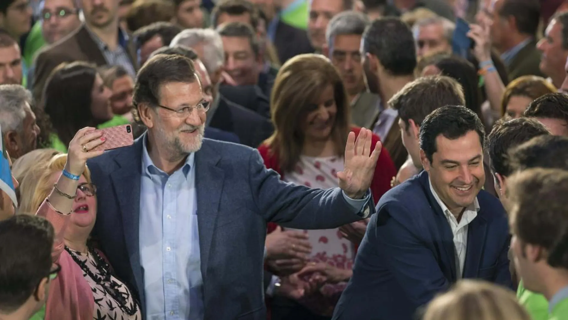 El presidente del Gobierno, Mariano Rajoy, y el candidato de esta formación a presidir la Junta de Andalucía, Juanma Moreno, saludan a los asistentes al comienzo del acto de presentación, hoy en Sevilla, de los 109 candidatos del PP al Parlamento de Andalucía