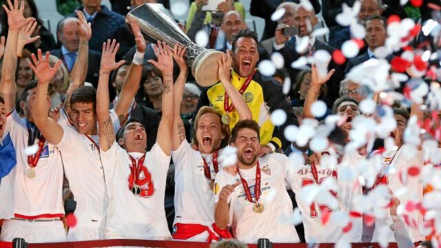 El capitán del Sevilla, Ivan Rakitic (c), sostiene el trofeo de campeones durante la celebración por la victoria ante el Benfica