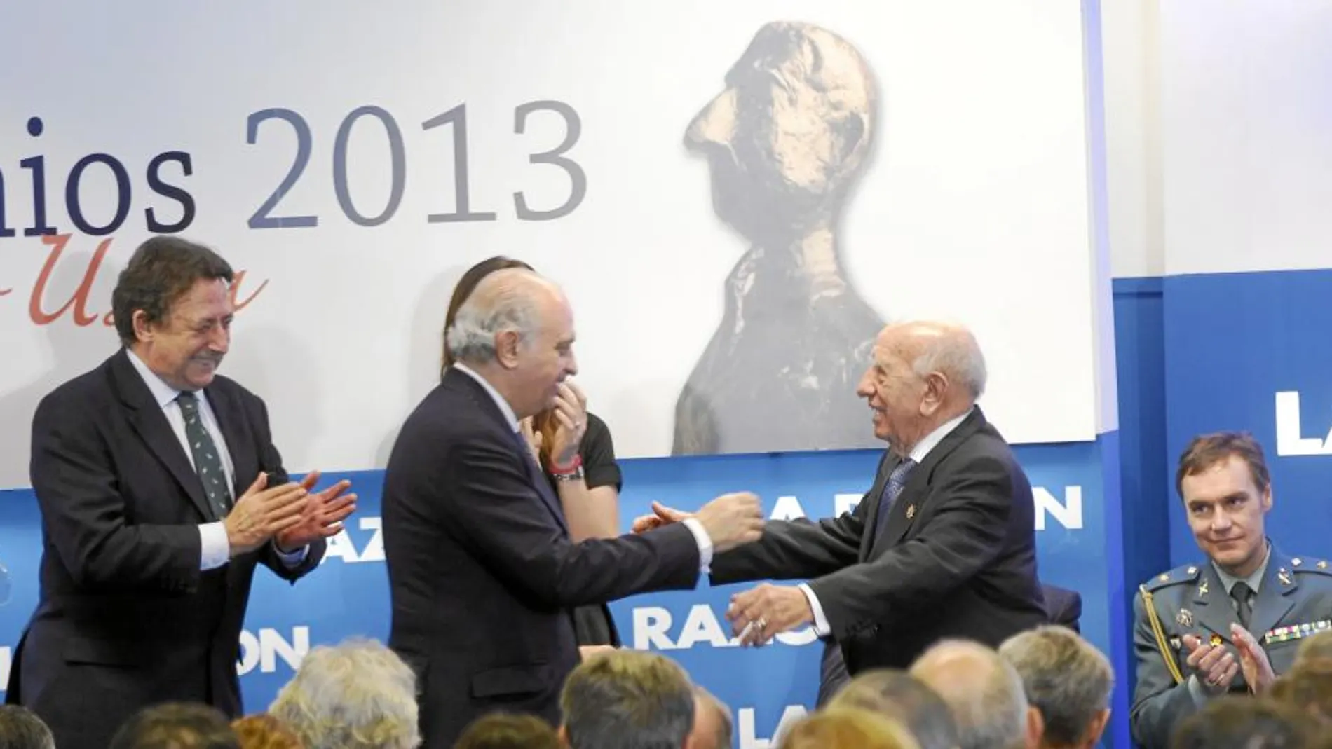 Victorino Martín Andrés recibe el galardón de manos del ministro del Interior, Jorge Fernández Díaz, ante la mirada de Alfonso Ussía