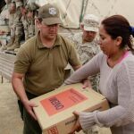 Miembros del Ejército de Chile entregan una caja con alimentos a una habitante de Pisagua afectada por el terremoto.