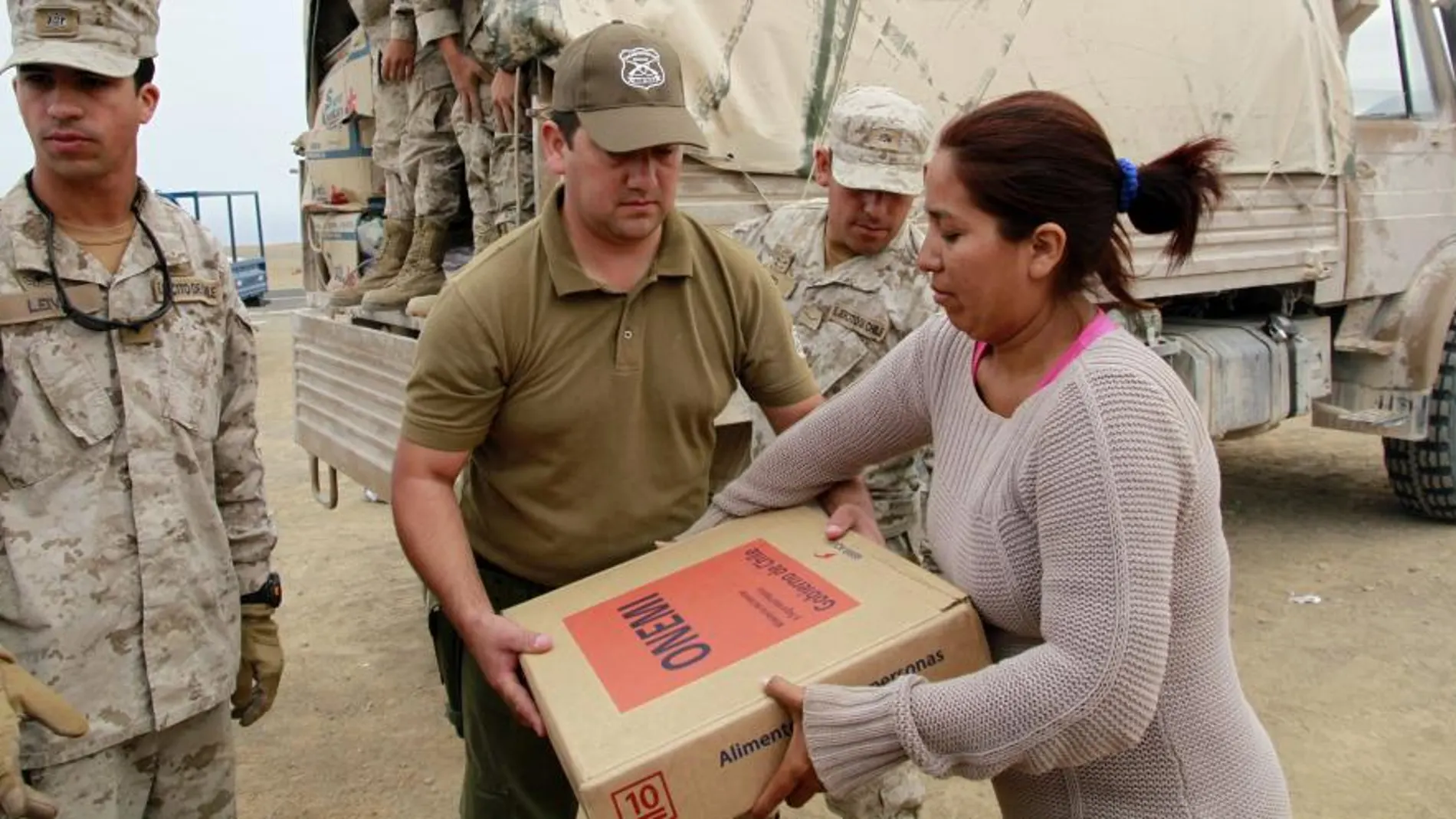 Miembros del Ejército de Chile entregan una caja con alimentos a una habitante de Pisagua afectada por el terremoto.