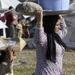 Una mujer yazidí y una niña llevan la colada sosteniéndola en sus cabezas en el campo de refugiados de Baharka, en Irak