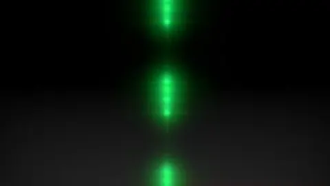 Representación de un sistema en el que se encierra un átomo entre dos espejos que confinan la luz. Al ser excitado con un láser, el sistema emite la luz a través de un número dado de fotones que puede fijarse a voluntad