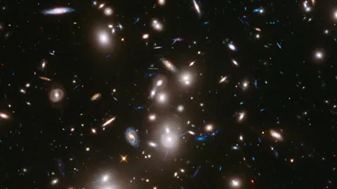 La exposición Hubble revela casi 3.000 de estas galaxias de fondo intercaladas con imágenes de cientos de galaxias en primer plano en el clúster