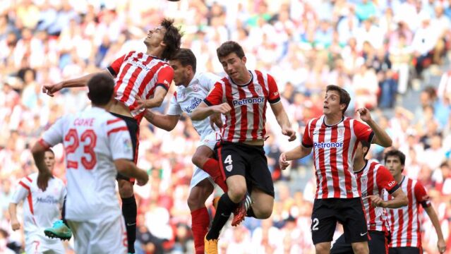 Los jugadores del Athletic de Bilbao, Ander Iturraspe (i) y Aymeric Laporte, (c), saltan a por el balón ante el defensa polaco del Sevilla FC, Grzegorz Krychowiak.