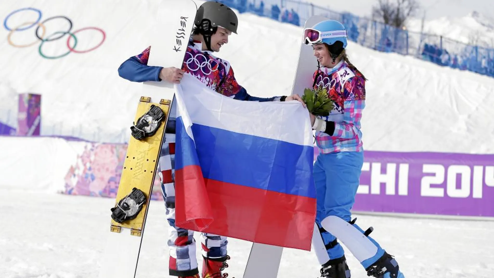 Vic Wild y Alena Zavarnina posan con una bandera rusa después de ganar sus medallas en Sochi