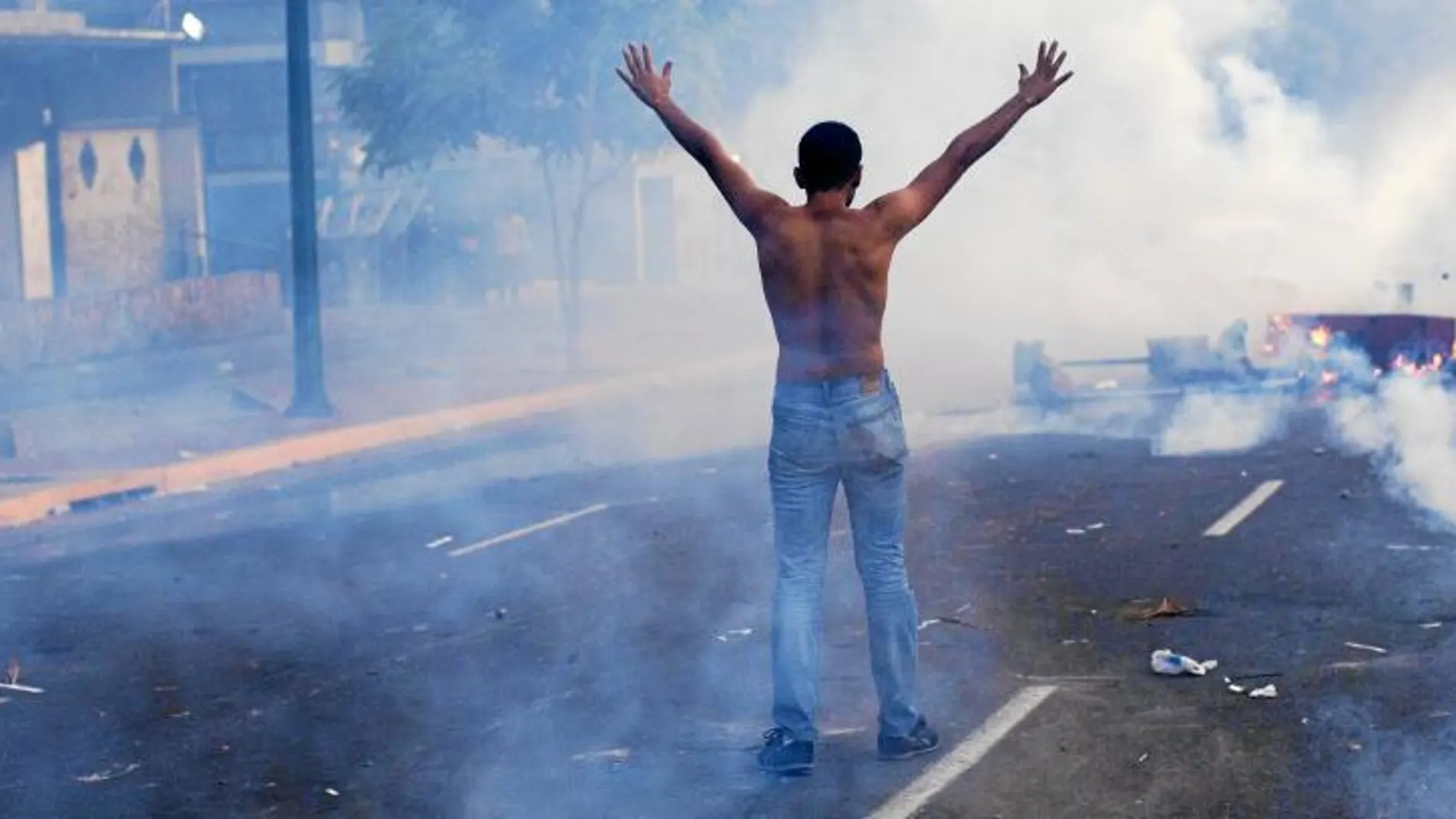 Un manifestante levanta los brazos delante la policía, durante una manifestación en Caracas