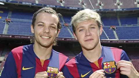 Fotografía cedida por el FC Barcelona de Louis Tomlinson (i) y el guitarrista irlandés Niall Horan (d), miembros del grupo musical One Direction, quienes posan con las camisetas del FC Barcelona durante su visita hoy al Camp Nou