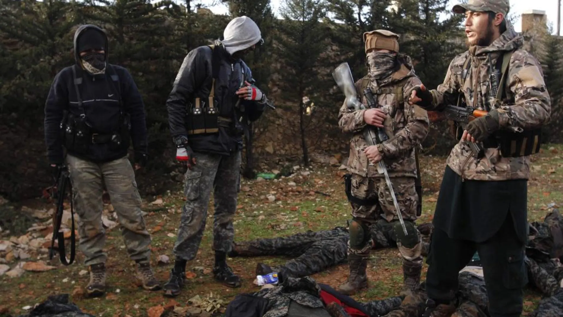 Combatientes rebeldes sirios junto a los supuestos cadáveres de soldados leales al gobierno Sirio