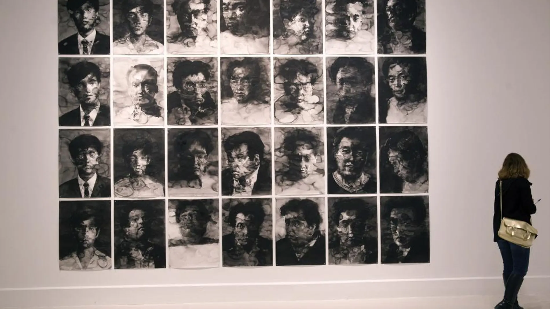 Una mujer frente a la obra titulada "Autoretratos", del artista francés de origen chino Yan Pei-Ming, que forma parte de la exposición "No comment", primera muestra de este creador en un museo español, y que se inaugura hoy en el Centro de Arte Contemporáneo (CAC) de Málaga